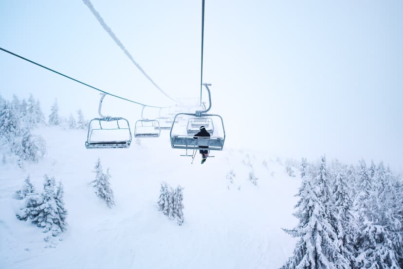 Snowy chair lift with a single skier on it