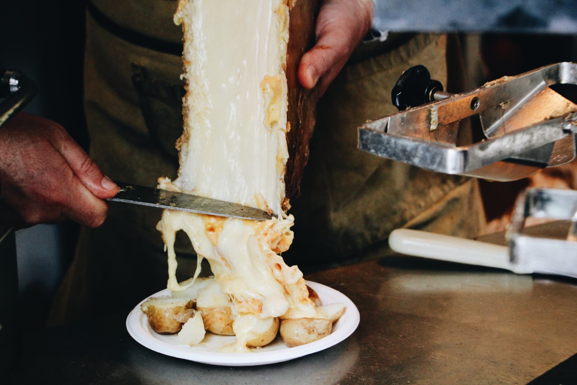 Waiter carves off raclette cheese to eat with potatoes at French ski resort